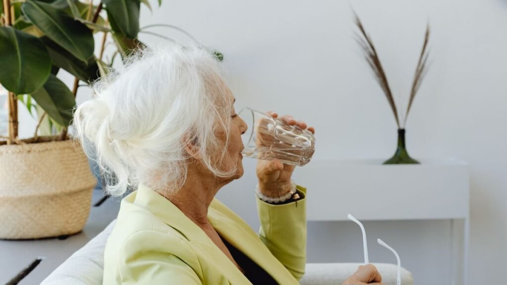 Senior buvant un verre d'eau lentement
