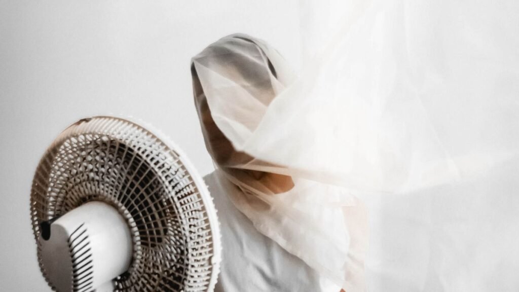 Personne se rafraîchissant avec un petit ventilateur